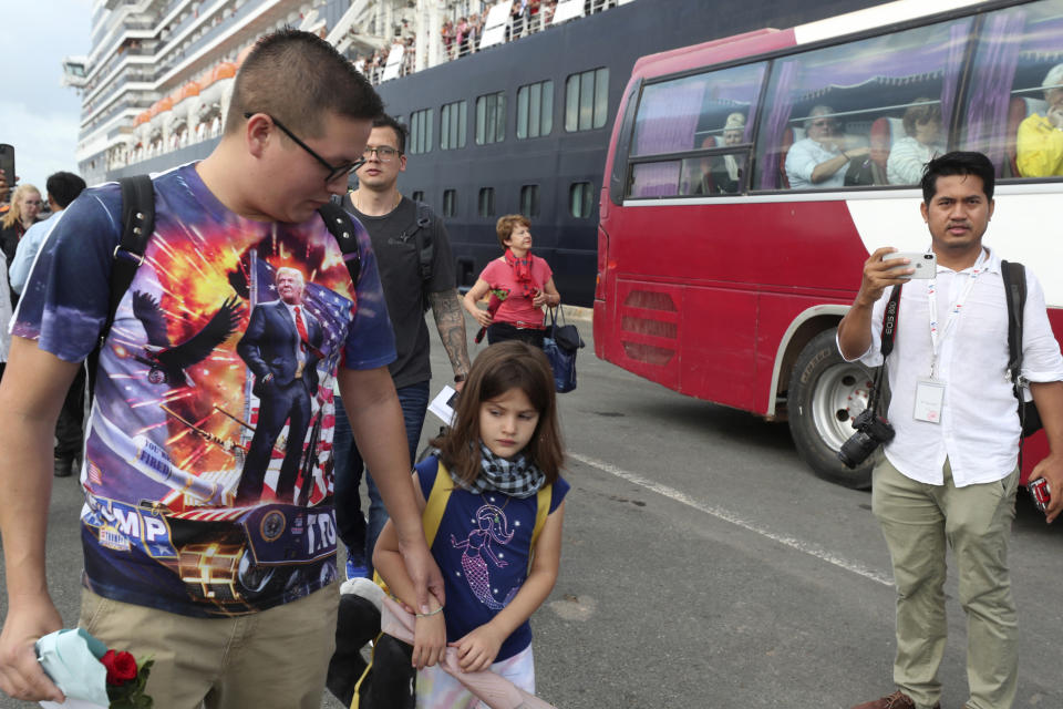 A passenger leads a girl after they disembarked from the MS Westerdam, owned by Holland America Line, at the port of Sihanoukville, Cambodia, Friday, Feb. 14, 2020. Passengers finally disembarked on Friday from the cruise ship allowed to dock in Cambodia following two weeks of being stranded at sea after being refused entry by four Asian governments because of virus fears. (AP Photo/Heng Sinith)