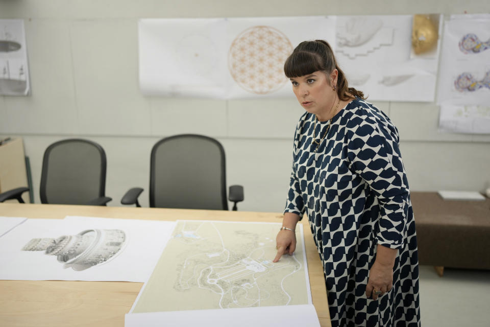 Portuguese artist Joana Vasconcelos points at a map of the gardens of Waddesdon Manor in southeast England where her most ambitious outdoor project yet will be located, at her studio in Lisbon, Friday, Nov. 11, 2022. The 51-year-old artist, renowned for her big, in-your-face installations, is now creating a ceramic wedding cake that's 12 meters high and 15 meters wide. (AP Photo/Armando Franca)