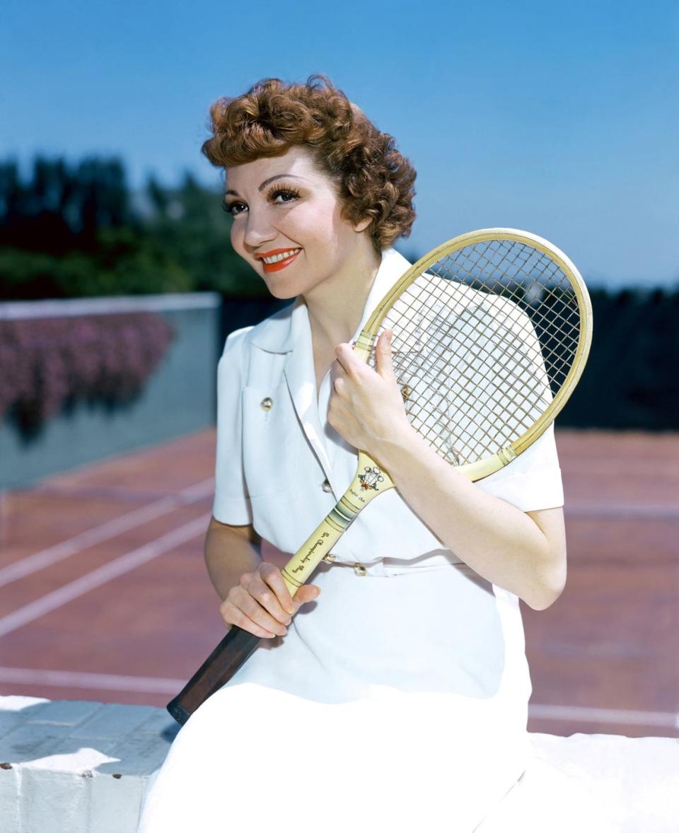 <p>Claudette Colbert wears her tennis whites as she gets ready to hit the court, circa 1930. </p>