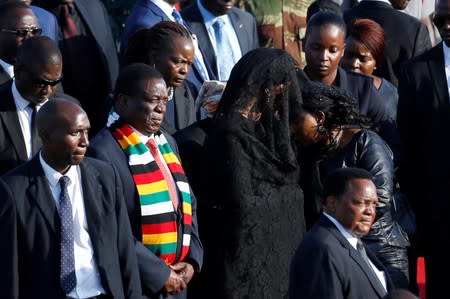 Zimbabwean President Emmerson Mnangagwa stands next to Grace Mugabe, after receiving the body of her husband, former Zimbabwean President Robert Mugabe in Harare