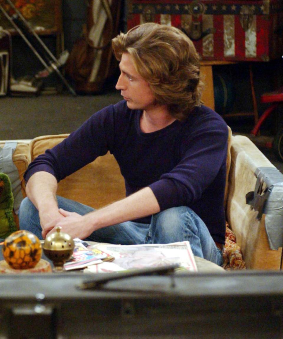 Randy sitting on a couch, talking, with various items on a coffee table in front of him