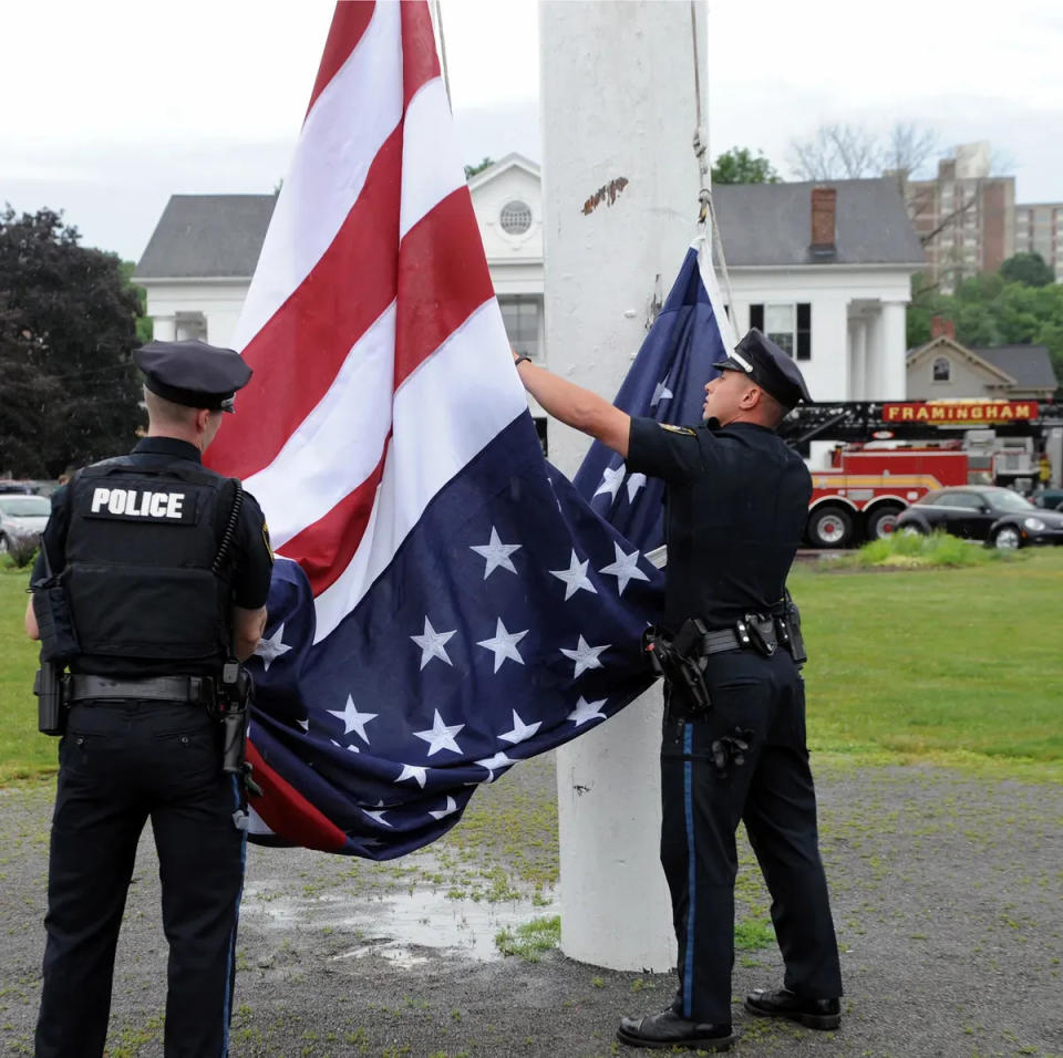 Framingham police officers Domenic Guarino, right, and Stephen Fowks take part in Flag Day ceremonies in 2021 on the Framingham Centre Common