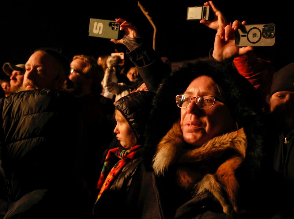 As others record the moment on their iPhones, Julie Miller, 52, of Sunfield, watches the Viking ship burn during the opening ceremony of the Michigan Nordic Fire Festival at the Eaton County Fairgrounds in Charlotte on Friday, Feb. 24, 2023.