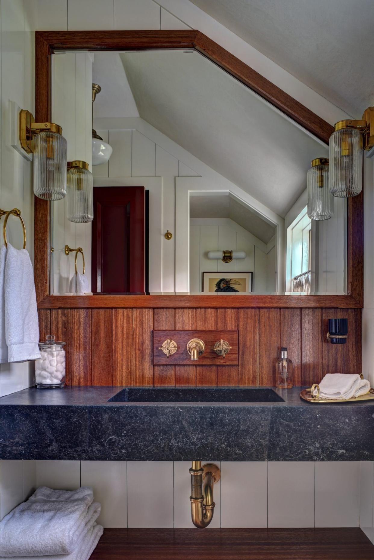 Nautical bathroom with wood and painted wall paneling, ship-inspired wall sconces and an angular mirror