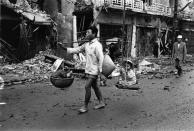 <p>A Vietnam War refugee returns to Hue, carrying two children in baskets suspended from his shoulder in March 1968. (Photo: Terry Fincher/Daily Express/Hulton Archive/Getty Images) </p>