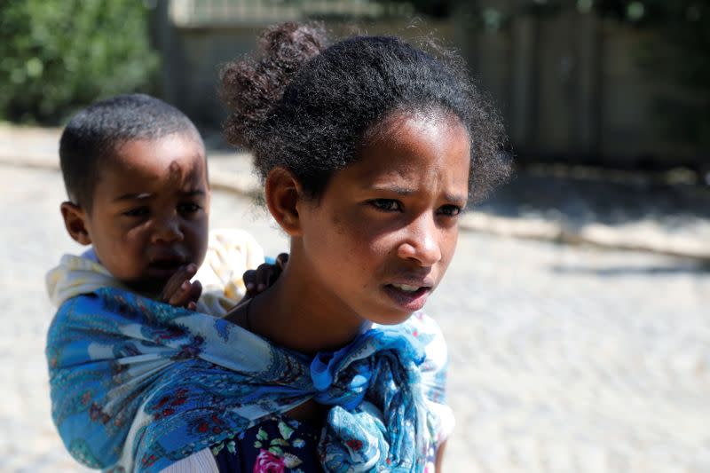 Mibrak Hailu, who says her parents were killed by Eritrean soldiers carries one of her five siblings, in the Tigray region