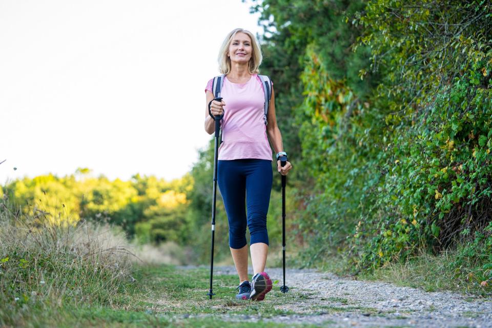 Woman using walking poles while on a trail.