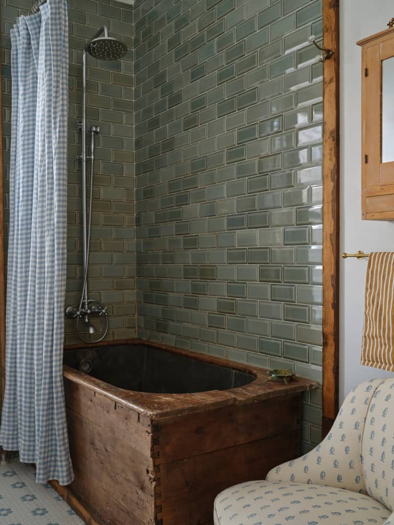 Vintage wooden tub in newly renovated bathroom with blue/gray subway tiles.