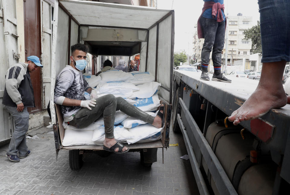 Palestinian workers load sacks of flour distributed by the United Nations Relief and Works Agency (UNRWA) on a tuk-tuk to distribute to poor refugee families at Sheikh Redwan neighborhood in Gaza City, Tuesday, March 31, 2020. The United Nations has resumed food deliveries to thousands of impoverished families in the Gaza Strip after a three-week delay caused by fears of the coronavirus. UNRWA, the U.N. agency for Palestinian refugees, provides staples like flour, rice, oil and canned foods to roughly half of Gaza’s 2 million people. (AP Photo/Adel Hana)