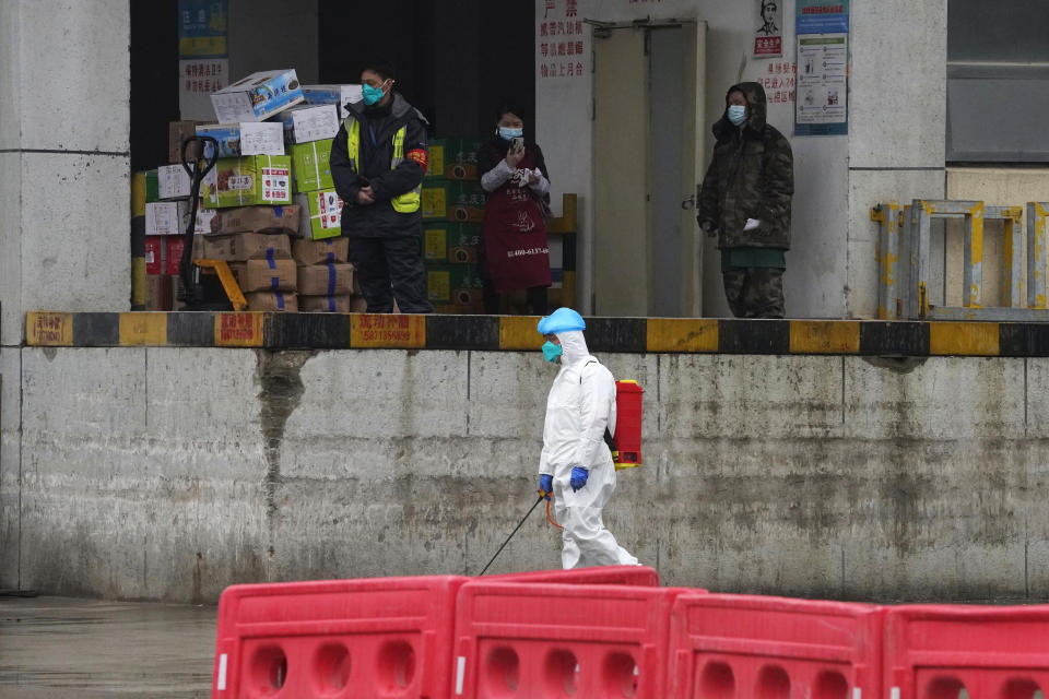 A worker in protective overall passes by a warehouse at the Baishazhou wholesale market during a visit by the World Health Organization on the third day of field visit in Wuhan in central China's Hubei province on Sunday, Jan. 31, 2021. (AP Photo/Ng Han Guan)