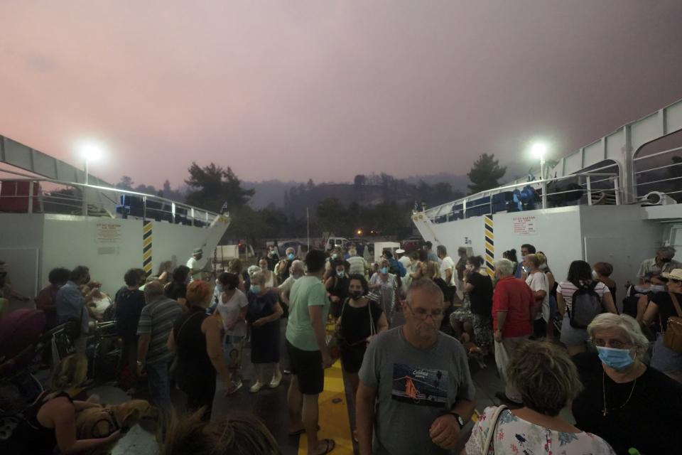 A crowd of people board a ferry taking them off Evia, Greece.