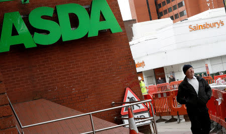 A man walks past branches of ASDA and Sainsbury's in Stockport, Britain April 30, 2018. REUTERS/Phil Noble/Files