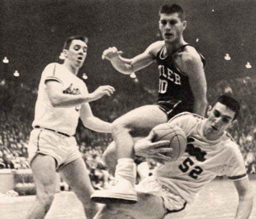 UE's Wayne Boultinghouse (left) looks on as Jerry Sloan (52) grabs a loose ball against Butler in 1963-64.