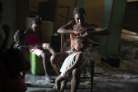 A woman braids a girl's hair at a school converted into a shelter after they were forced to leave their homes due to clashes between armed gangs, in the Tabarre neighborhood of Port-au-Prince, Haiti, Thursday, May 12, 2022. UNICEF's representative in Haiti said that one growing concern is the lack of access to basic things like water, food and medicine as people remain trapped in certain areas while gangs continue to fight, noting that malnutrition is on the rise. (AP Photo/Odelyn Joseph)