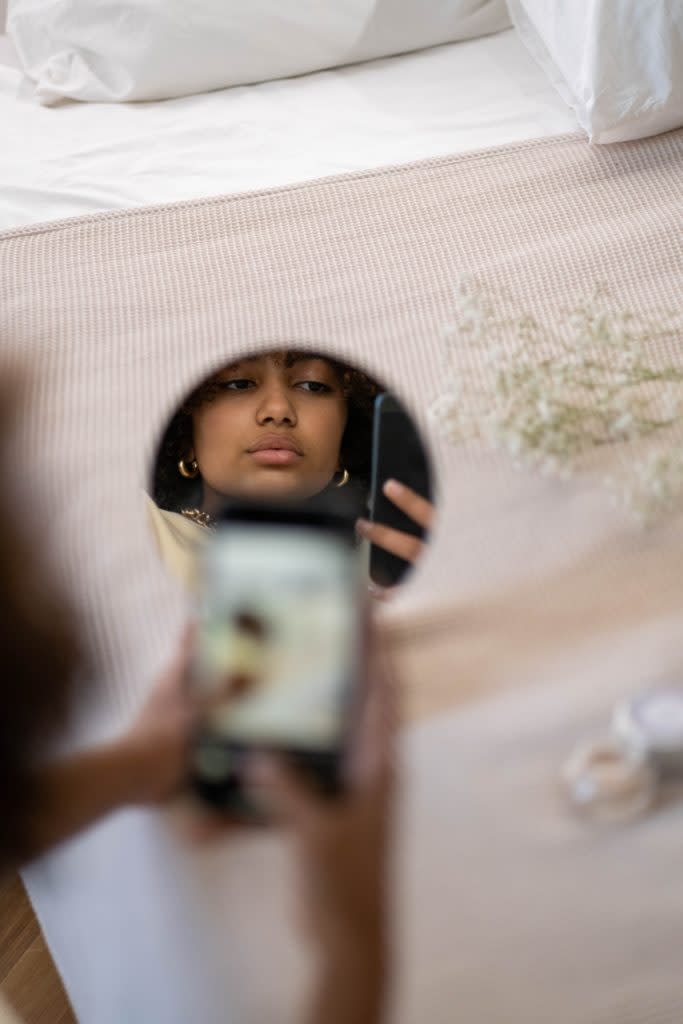 Reflection of a Black woman looking at her cell phone