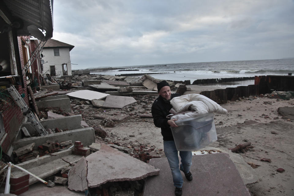 Peter Andrews removes belongings from his father's beachfront home, destroyed in the aftermath of a storm surge from the superstorm Sandy, Tuesday, Oct. 30, 2012, in Coney Island's Sea Gate community in New York. Andrews, 40, who was born in the house, said "we had a lot of storms and the only damage in the past was when a national guardsman threw a sandbag through the window." He added, the house was in the process of being sold. (AP Photo/Bebeto Matthews)