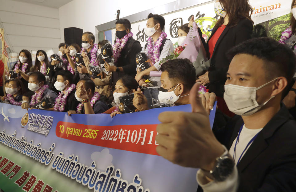 First group of foreign travelers pose for photos after arriving at Taoyuan International Airport in Taoyuan, Northern Taiwan, Thursday, Oct. 13, 2022. Taiwan announced that it will end mandatory COVID-19 quarantines for people arriving from overseas beginning Oct. 13. The Central Epidemic Command Center announced that the previous weeklong requirement will be replaced with a seven-day self-monitoring period. (AP Photo/Chiang Ying-ying)