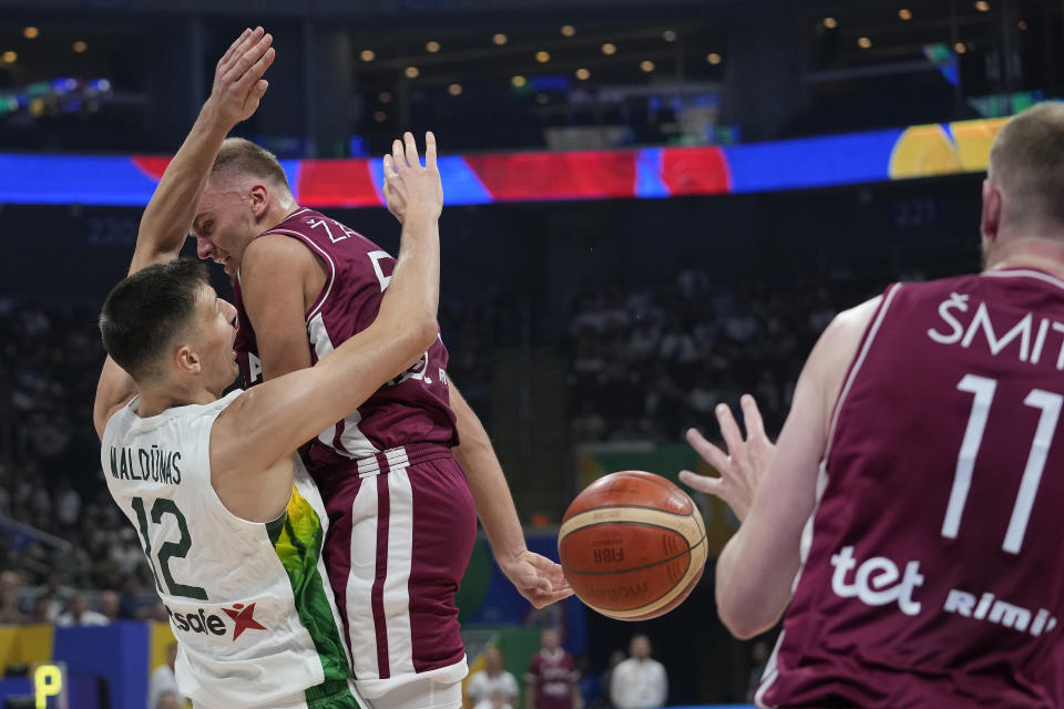 Latvia guard Arturs Žagars (55) passes the ball in front of Lithuania center Gabrielius Maldunas (12) during the Basketball World Cup classification match in Manila, Philippines, Saturday, Sept. 9, 2023. (AP Photo/Aaron Favila)