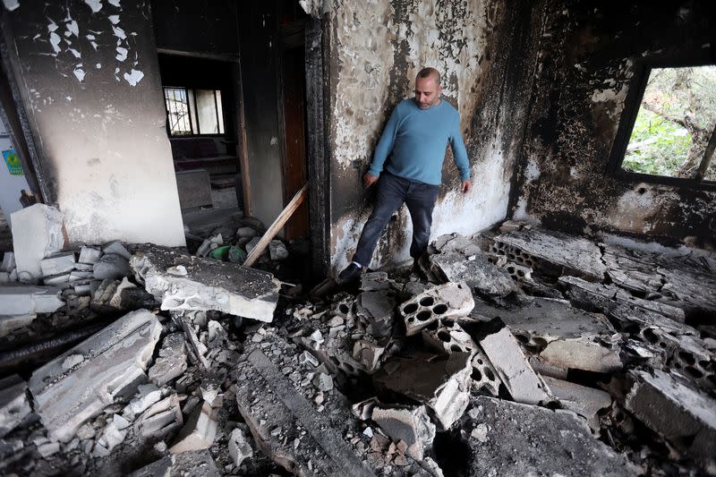 Fawzi Jaber walks on the rubble of his damaged house in Mhaibib