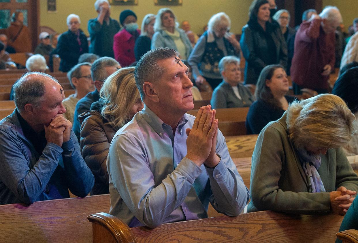 Parishioners pray after receiving ashes by Father Mark Capiuzzi, at St. Andrew Catholic Church, in Newtown, on Wednesday, March 2, 2022.