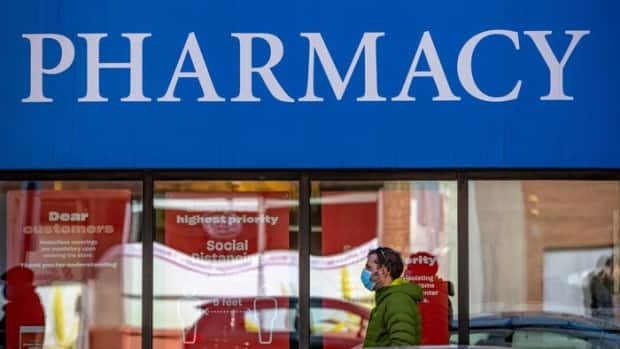 A man wearing a mask walks past a pharmacy in Ottawa earlier this month. As of April 12, around 80 additional city pharmacies will be able to vaccinate people 55 and older against COVID-19. (Mathieu Theriault/Radio-Canada - image credit)