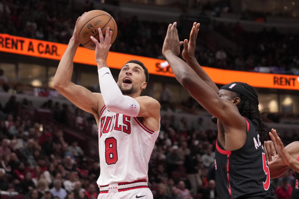 Chicago Bulls' Zach LaVine(8) drives to the basket past Precious Achiuwa, right, during the first half of an NBA basketball game Friday, Oct. 27, 2023, in Chicago. (AP Photo/Charles Rex Arbogast)