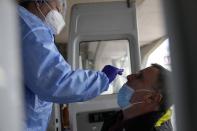 A member of the medical staff at the National Public Health Organisation (EODY) conducts a COVID-19 rapid test on a man in Athens, Greece, Wednesday, Dec. 29, 2021. A government committee of medical experts hold an emergency meeting Wednesday to consider speeding up scheduled restrictions after the daily number of COVID-19 infections more than doubled in a day to set a new record. (AP Photo/Thanassis Stavrakis)