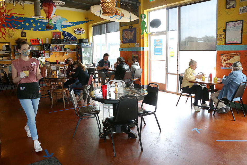 Server Delaney Fine, left, brings some drinks to customers at the Squeeze In restaurant in Reno on May 13, 2020.