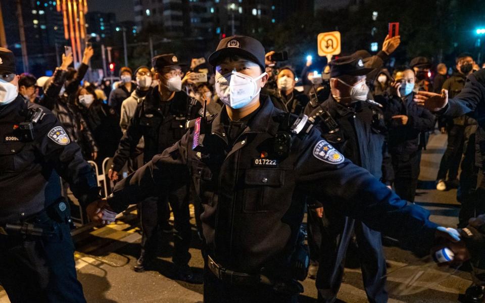 Police officers stand guard during a protest in Beijing - Bloomberg