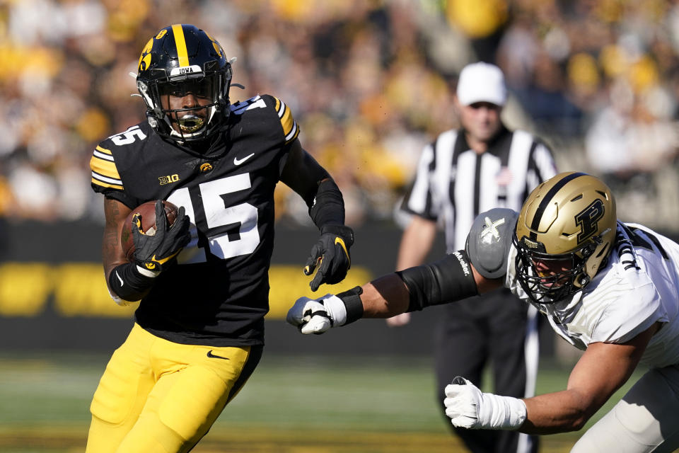 Iowa running back Tyler Goodson (15) runs from Purdue defensive end George Karlaftis, right, during the first half of an NCAA college football game, Saturday, Oct. 16, 2021, in Iowa City, Iowa. (AP Photo/Charlie Neibergall)