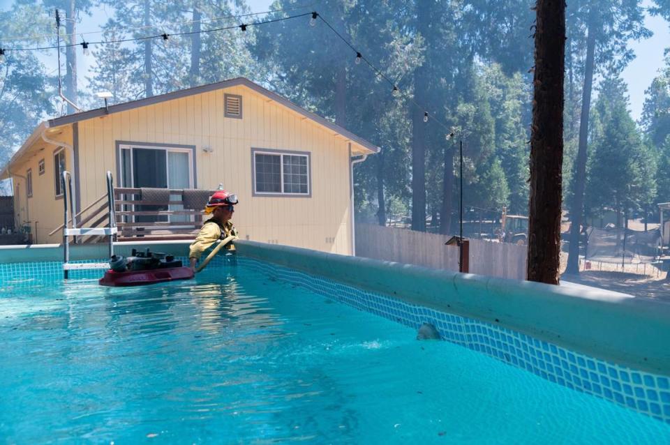 Capt. Robert Klemek with the Monterey Fire Department watches as two of his firefighters use water drawn from an above-ground pool to put out hotspots in Cohasset on Friday, July 26, 2024. “We’re in the wilderness. Lakes and streams are great; there’s not a whole lot around,” Klemek said. “We look for any water source possible, whether it’s a pool, a hot tub. So we try to utilize what we can smartly.”