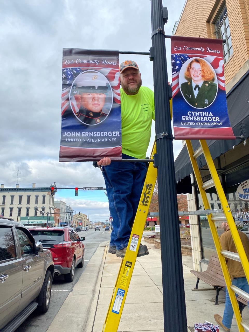 John Ernsberger pauses hangs banners honoring local veterans along Sandusky Avenue in Bucyrus in 2022. The banner is similar to how the banners in Galion and other communities in the area look as well.