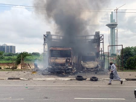 A man runs past burning vehicles after clashes between police and Shi'ite protesters in Abuja