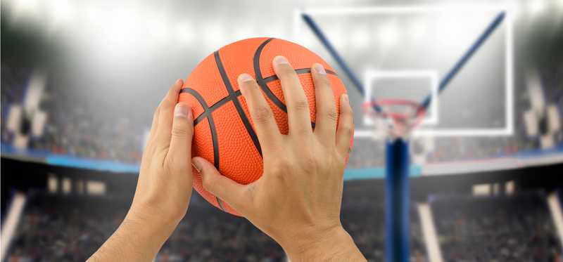 Hands hold a basketball to shoot it.