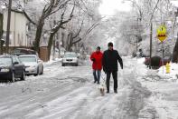 Residents tread ice-covered road as the walk dogs after freezing rain in Toronto, Ontario December 22, 2013. Thousands of households are without power in the Greater Toronto area following an overnight ice storm. REUTERS/Hyungwon Kang (CANADA - Tags: ENVIRONMENT ANIMALS)