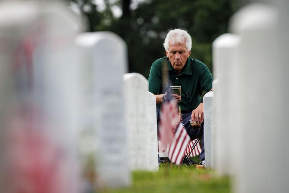 A man kneels at the resting place of a fallen loved one in Arlington National Cemetery on Memorial Day.