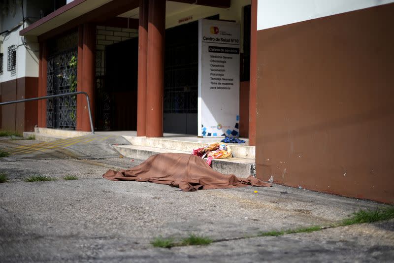 A body covered by a sheet lies outside of a health center of Ecuador's Public Health Ministry amid the spread of the coronavirus disease (COVID-19), in Guayaquil