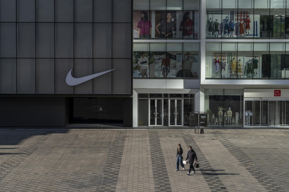 A woman and a man walk in a quiet shopping area where shops have been closed, on May 13, 2022, in Beijing, China.