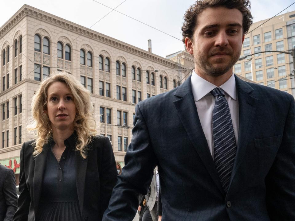 Elizabeth Holmes, center, and her partner, Billy Evans, walk to court in San Jose for her sentencing hearing November 18, 2022