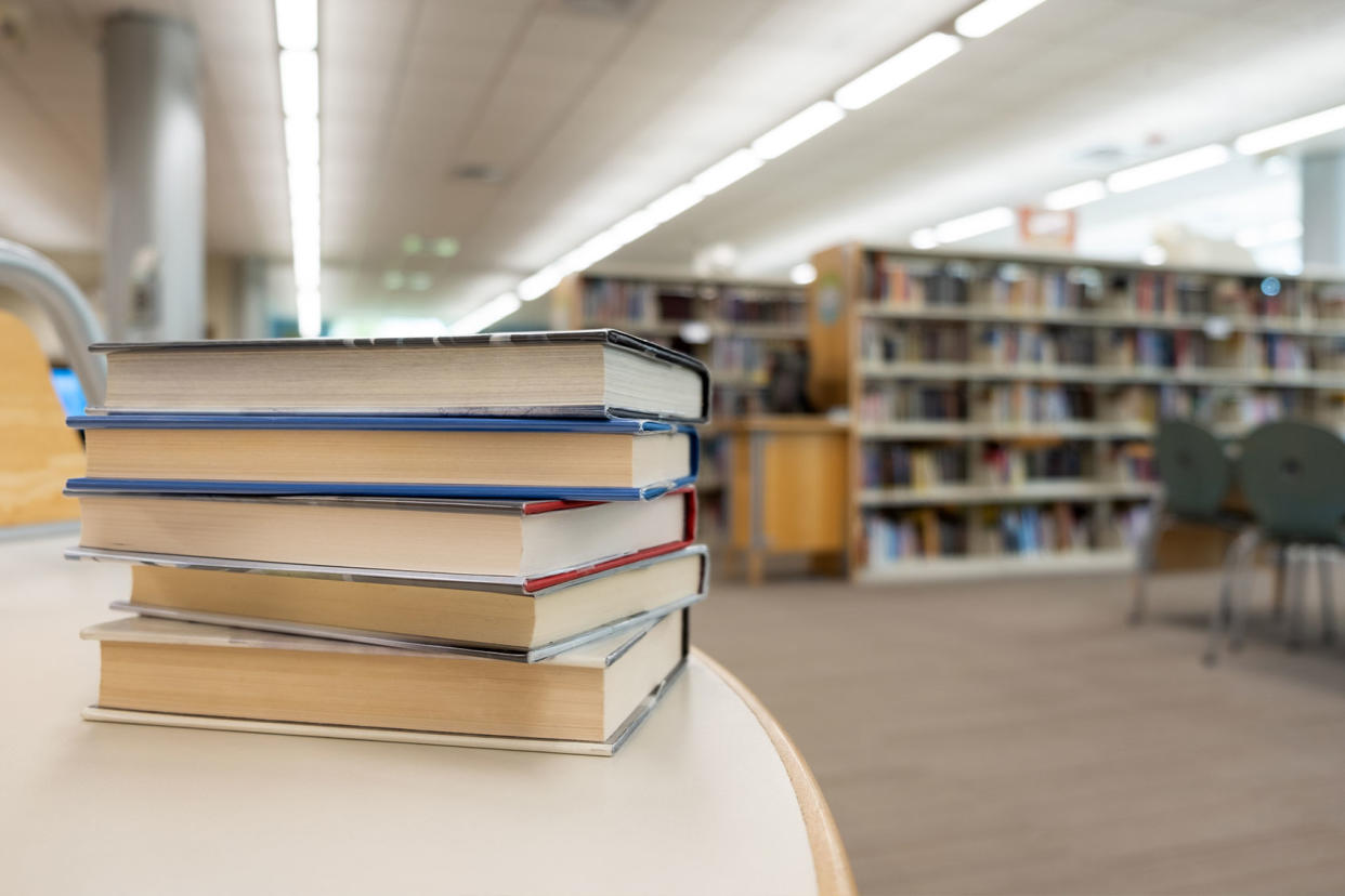 Stack of books on table at library Getty images/Kenishirotie