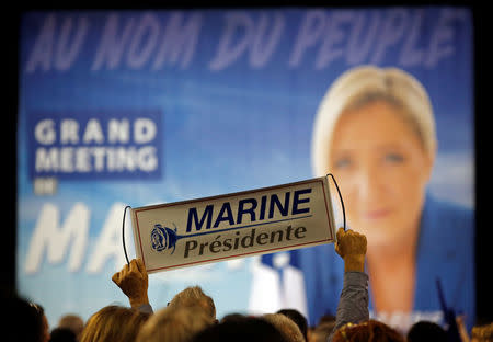 A supporter holds a poster to support Marine Le Pen, French National Front (FN) political party leader and candidate for French 2017 presidential election, during a political rally in Perpignan, France, April 15, 2017. REUTERS/Jean-Paul Pelissier