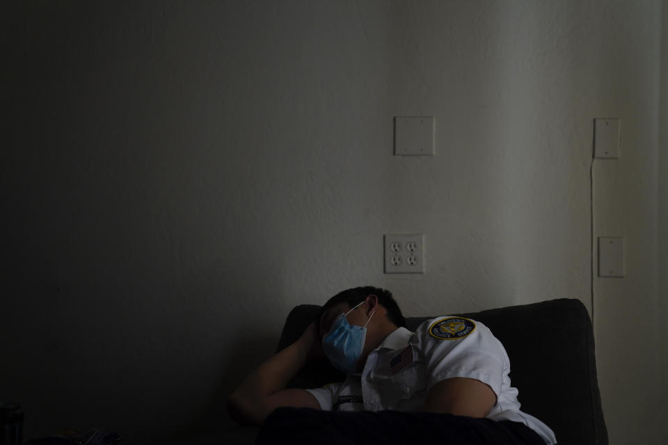 Emergency medical technician Thomas Hoang, 29, of Emergency Ambulance Service, falls asleep in a recliner while on standby for a dispatch call in Placentia, Calif., Saturday, Jan. 9, 2021. (AP Photo/Jae C. Hong)