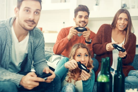 Friends holding controllers while playing a video game.