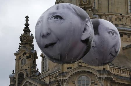 Balloons made by the 'ONE' campaigning organisation depicting German Chancellor Angela Merkel (L) and British Prime Minister David Cameron, leaders of the countries members of the G7 are pictured in front of the Frauenkirche cathedral in Dresden, Germany, May 27, 2015. REUTERS/Fabrizio Bensch