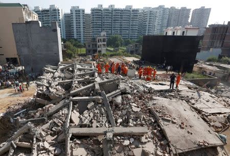 Rescue workers look for survivors amidst the rubble at the site of a collapsed residential building at Shah Beri village in Greater Noida, July 18, 2018. REUTERS/Adnan Abidi