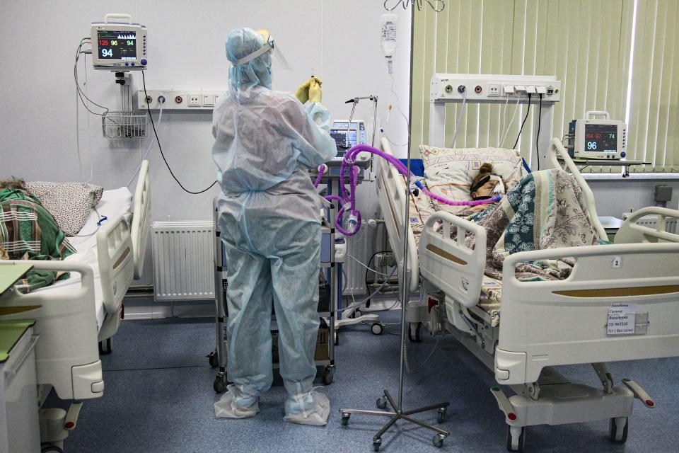 A medical worker wearing a special suit to protect against COVID-19 treats a patient at an ICU in Infectious Hospital No. 23 in Nizhny Novgorod, Russia, on Wednesday, Oct. 20, 2021. The low vaccination rate in Russia, where only about a third of the population is fully vaccinated, is causing concern as the country suffers a sharp rise in cases, setting records for infections and deaths nearly every day this month. (AP Photo/Roman Yarovitcyn)