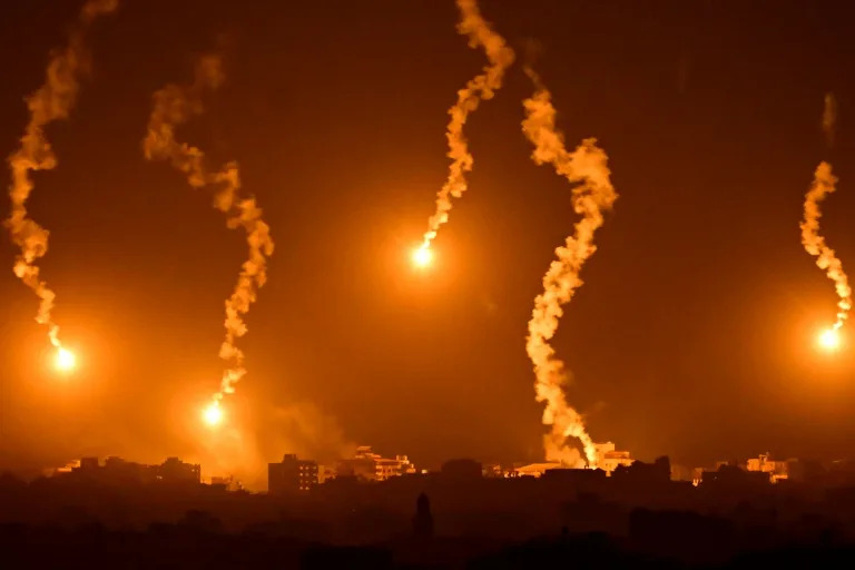 Flares dropped by Israeli forces illuminate the night sky above the Gaza Strip (Aris MESSINIS)