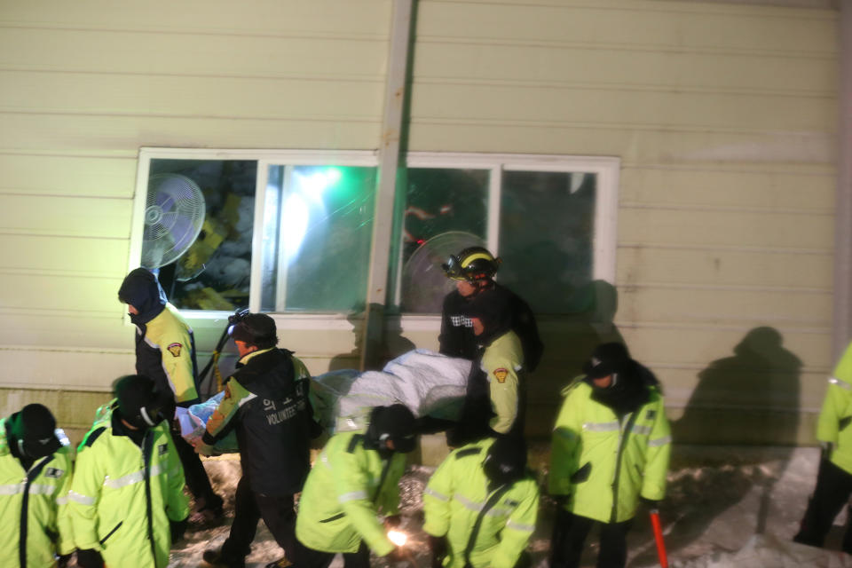 Rescue workers carry a body from a collapsed building in Gyeongju, South Korea, Monday, Feb. 17, 2014. South Korean police and news reports say that dozens of university students are feared trapped after a building’s roof collapsed because of recent heavy snowfall.(AP Photo/Yonhap, Lee Sang-hyun) KOREA OUT