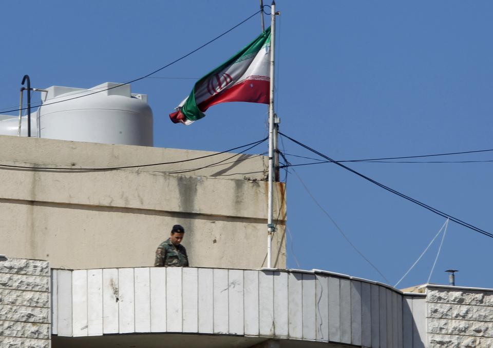 A Lebanese army soldier stands near a torn Iranian flag fluttering atop the Iranian cultural centre at the site of an explosion in the southern suburbs of Beirut February 19, 2014. (REUTERS/Sharif Karim)