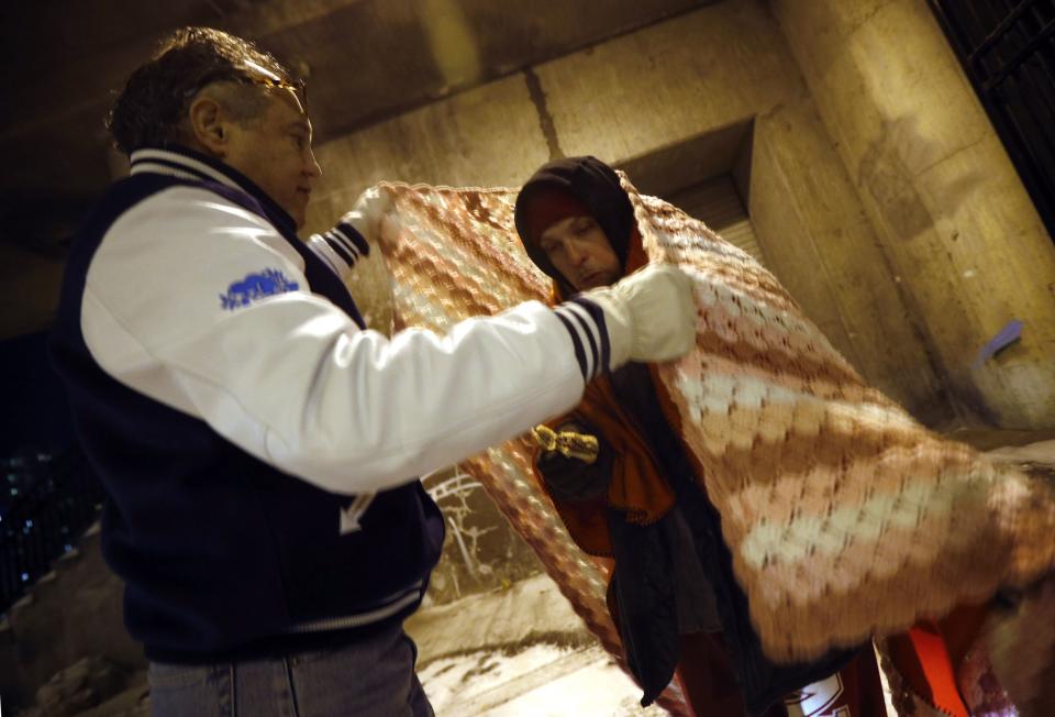 Doctor Angelo wraps homeless man in blankets under the overpasses on Lower Wacker Drive in Chicago